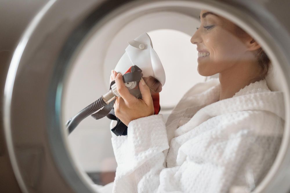 A lady clutching an oxygen mask in a hyperbaric chamber