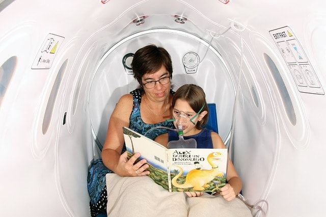 Elder lady reads to a child in a hyperbaric chamber